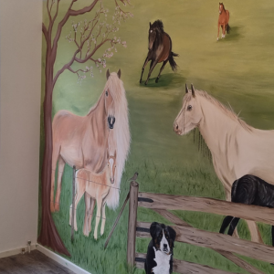 Een muurschildering van een uitzicht met paarden en honden. Het zijn de dieren van de eigenaar zelf, dit maakt het een persoonlijke unieke muurschildering